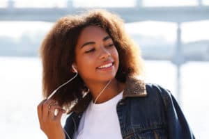 smiling young woman listening to headphones outside