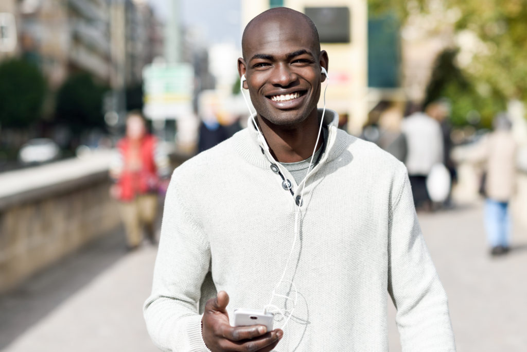 black man walking, listening to music, smiling