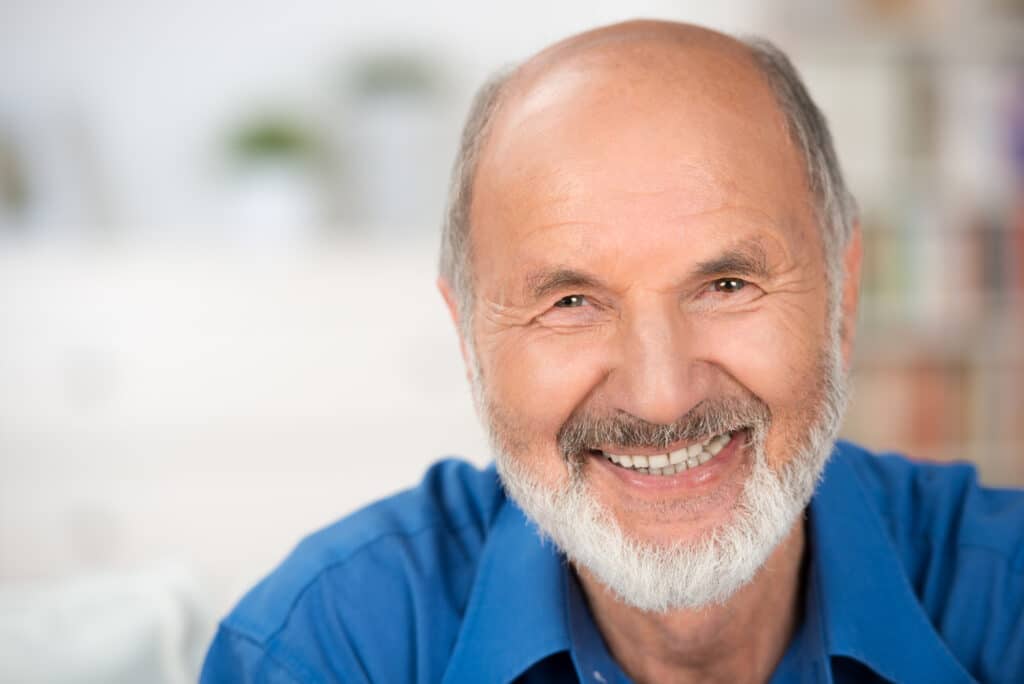 Close up portrait of a smiling attractive senior man looking directly at the camera with copyspace