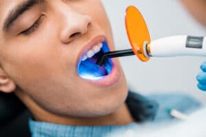 man sitting in chair with dental laser in his open mouth during gum disease treatment