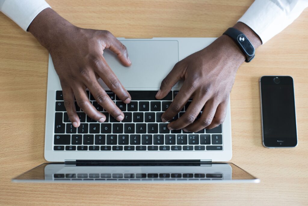 overhead picture of black man's hands typing on laptop