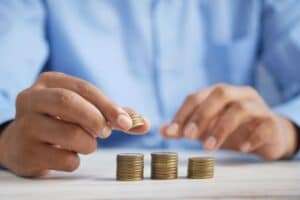 man in blue shirt stacking pennies on white table