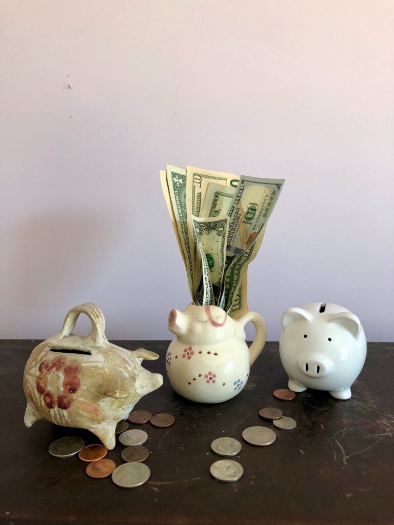 money and piggy banks on a table to convey affordable dental care in Austin, TX