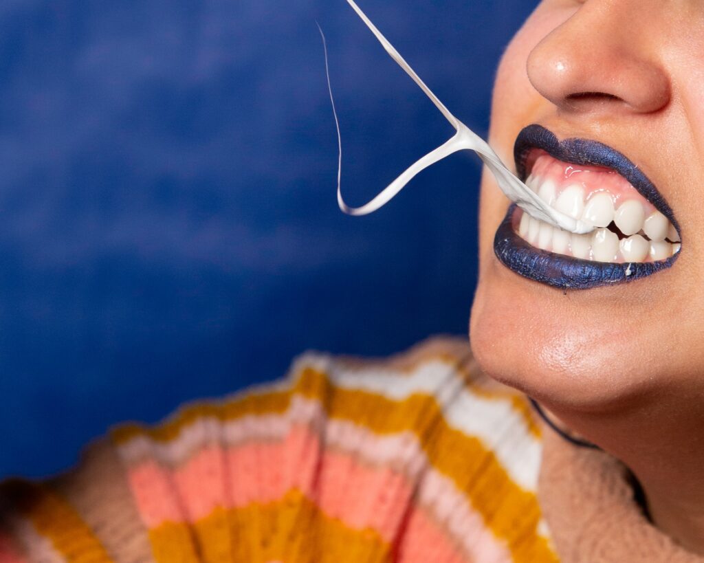 close up of woman's teeth, gums, and lips while pulling gum out of her mouth