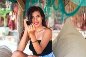 woman in black top on beach looking and smiling at the camera