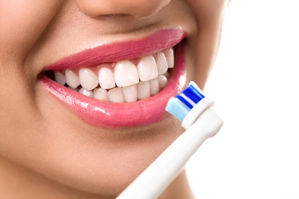 close up of perfect and healthy teeth with electric toothbrush