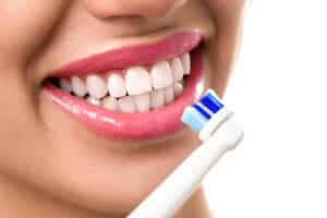 close up of perfect and healthy teeth with electric toothbrush