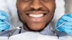 black man smiling in dental chair undergoing tooth bonding procedure