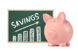 savings chart on chalk board next to a piggy bank