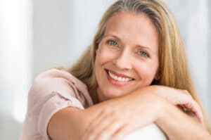 middle-age blonde woman resting head on her arms, smiling