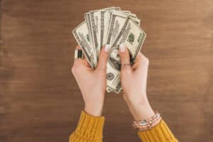 woman holding hundred dollar bills in her hands